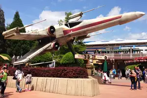A large model X-wing from the movie Star Wars mounted above passersby in Disneyland, Paris.