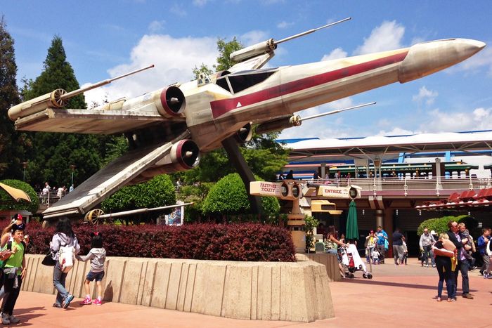 A large model X-wing from the movie Star Wars mounted above passersby in Disneyland, Paris.