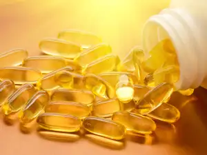 Vitamin D supplements falling out of a pill bottle.
