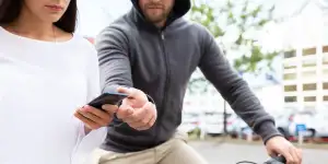 A man on a bicycle grabs a phone from a woman.