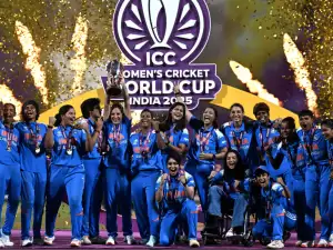 India women's cricket team celebrates with the World Cup trophy as gold confetti falls.