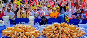 Plates of hot dogs in front of a crowd at a hot dog eating contest.