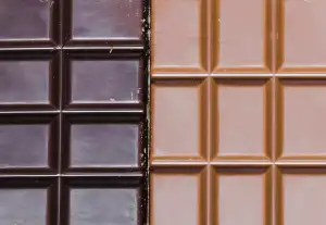 A close-up photo of two blocks of chocolate. One is milk chocolate and the other is dark chocolate.