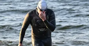 Bartłomiej Kubkowski in a wetsuit emerges from the water.