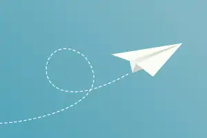 A white paper airplane against a blue background, with a dashed white flight path looping behind it.