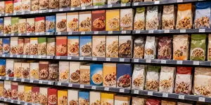A supermarket shelf filled with many different boxes and bags of cereal or granola.